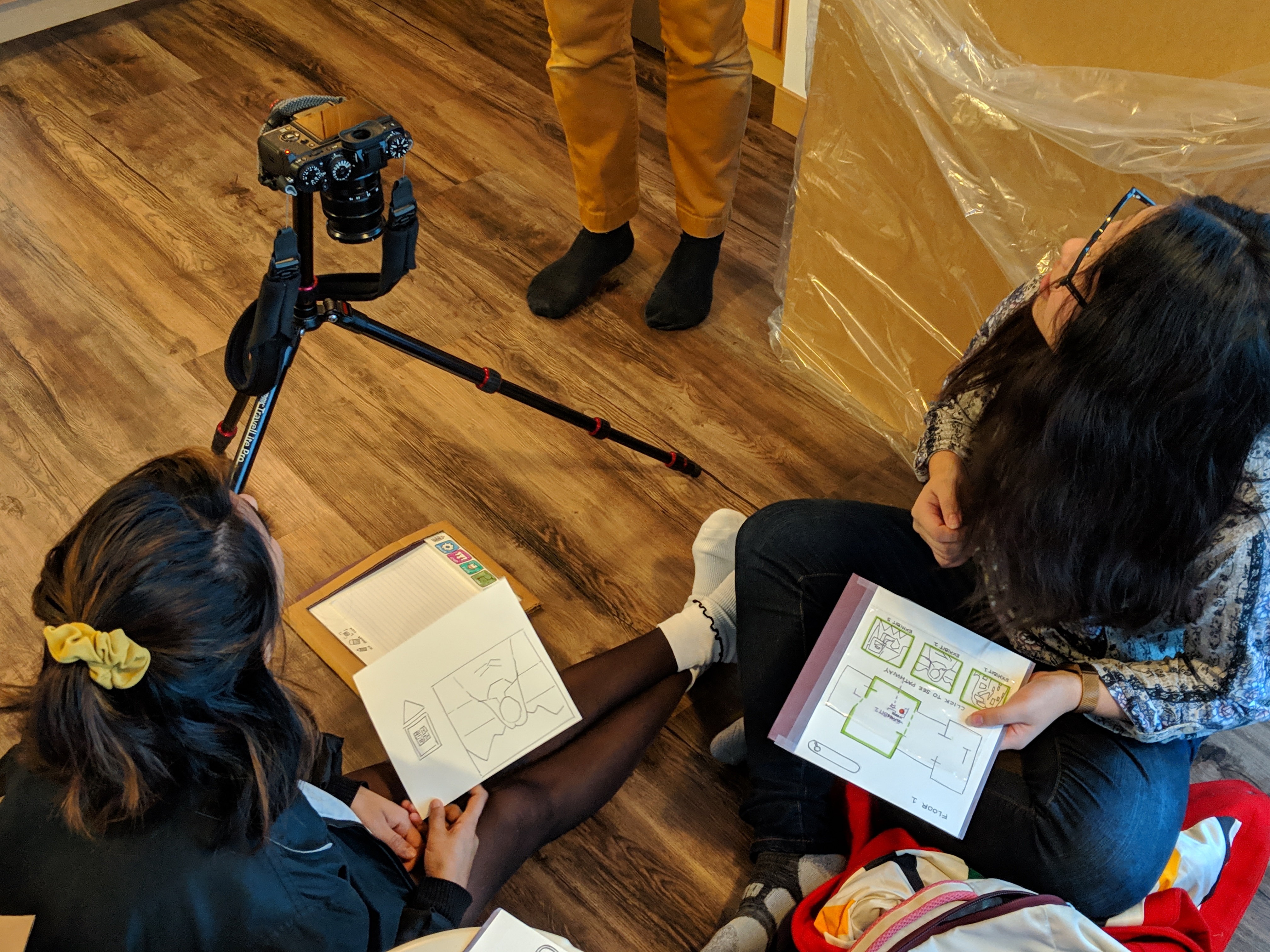 Image of Vishaka and Annie taking pictures of the paper prototype